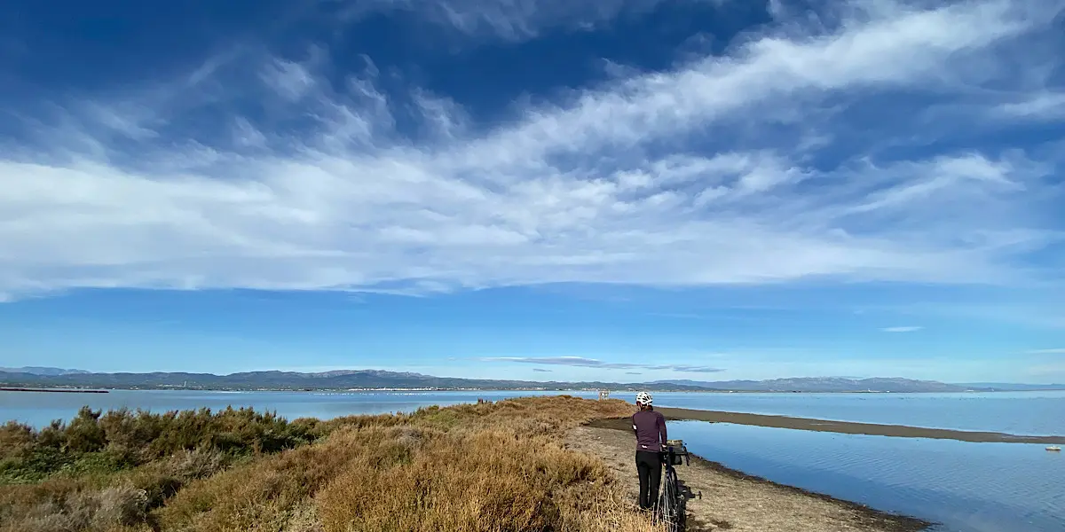 Ciclista de bikepacking en una pista junto a las lagunas del Delta del Ebro