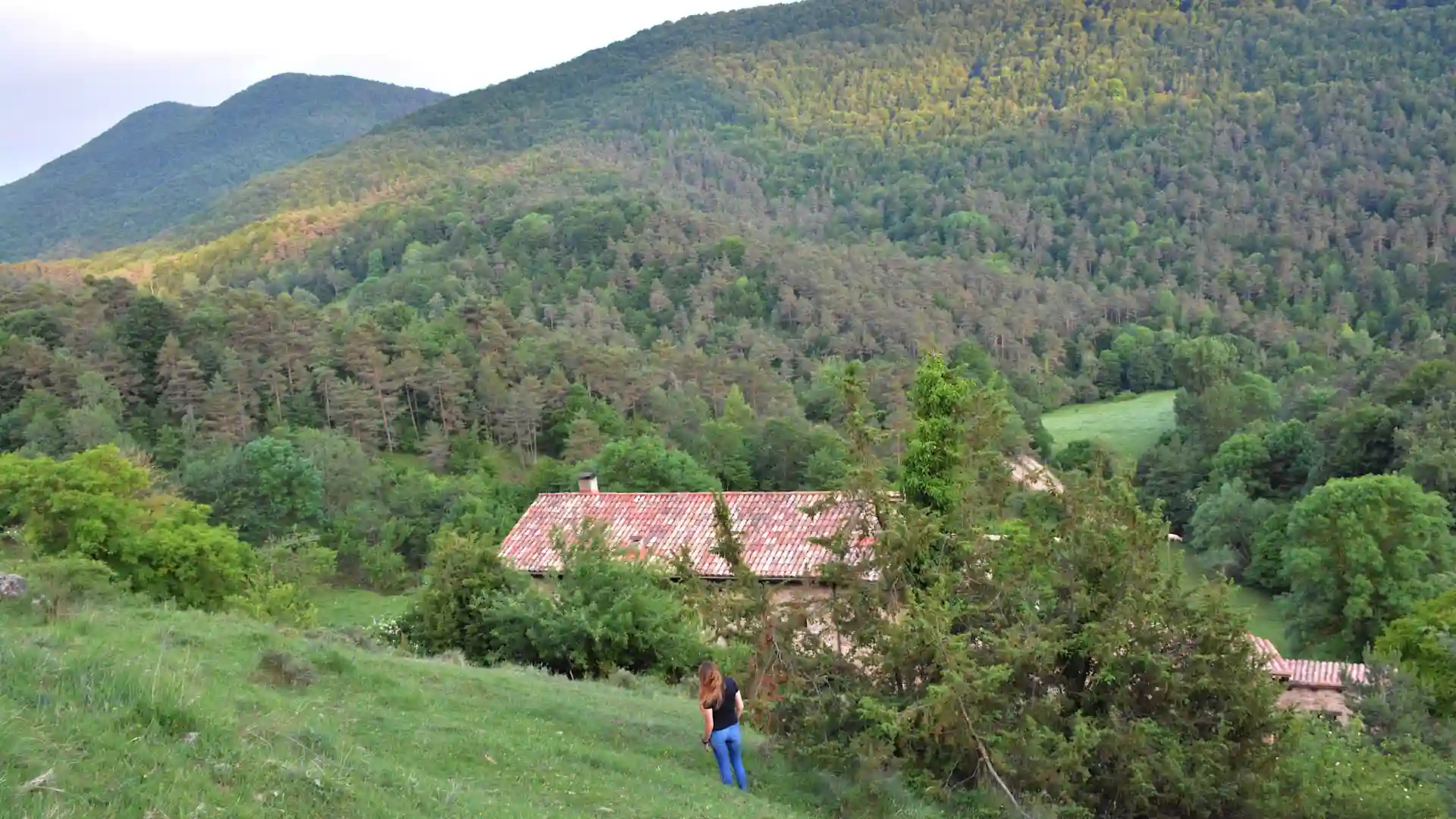 Cristina caminando por la pradera con vistas al entorno natural de Mas Guillamet. Casa Rural en el Ripollès